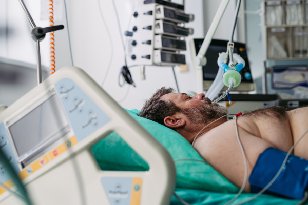 Intubated male patient lying unconscious in intensive care unit