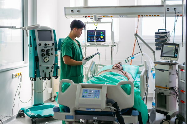 Doctor taking care of unconscious patient in hospital bed. Intensive care unit.