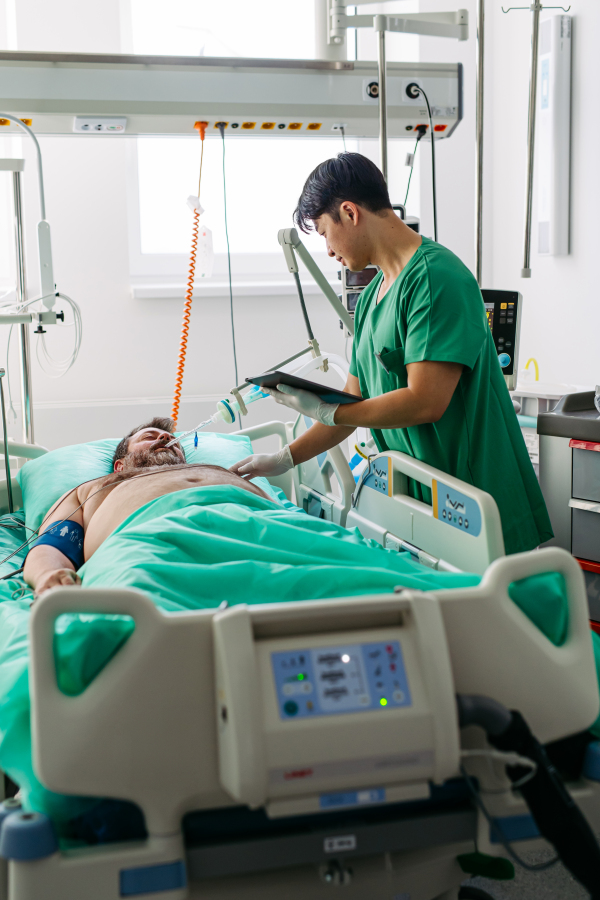 Doctor taking care of unconscious patient in hospital bed. Intensive care unit.