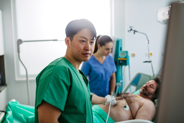 Medical professional using ultrasound probe in intensive care, abdominal ultrasound.