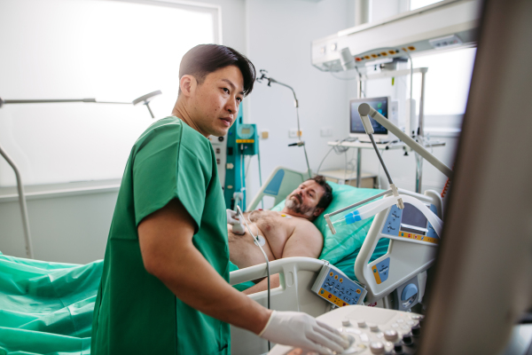 Doctor holding ultrasound transducer during abdominal ultrasound.