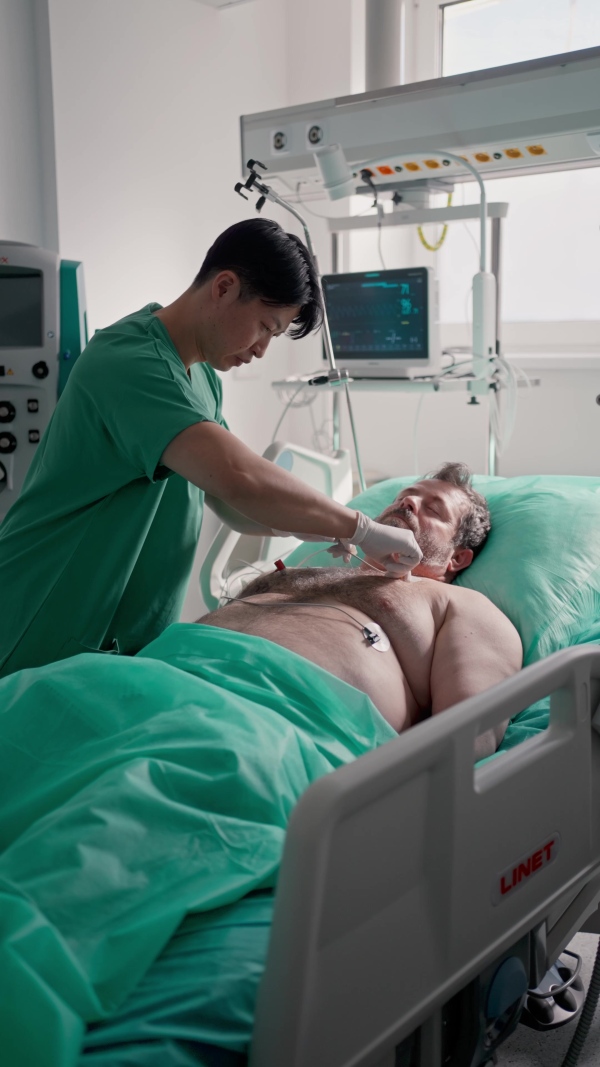 Doctor taking care of unconscious patient in hospital bed. Intensive care unit.