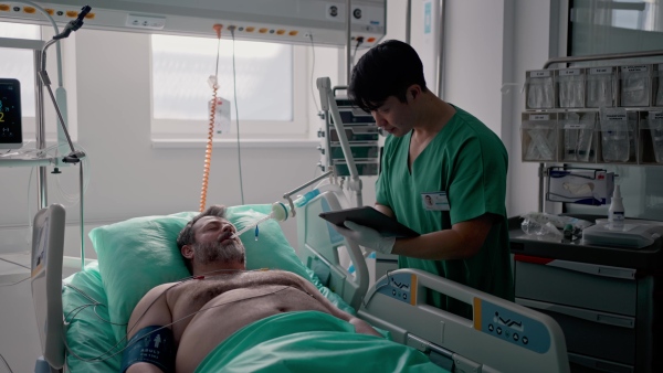 Doctor taking care of unconscious patient in hospital bed. Intensive care unit.