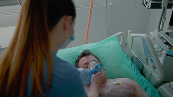 Medical team providing oxygen ventilation to unconscious patient in hospital.