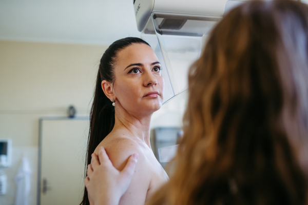 Nurse adjusts the patient for accurate breast imaging. Preventive breast cancer screening.