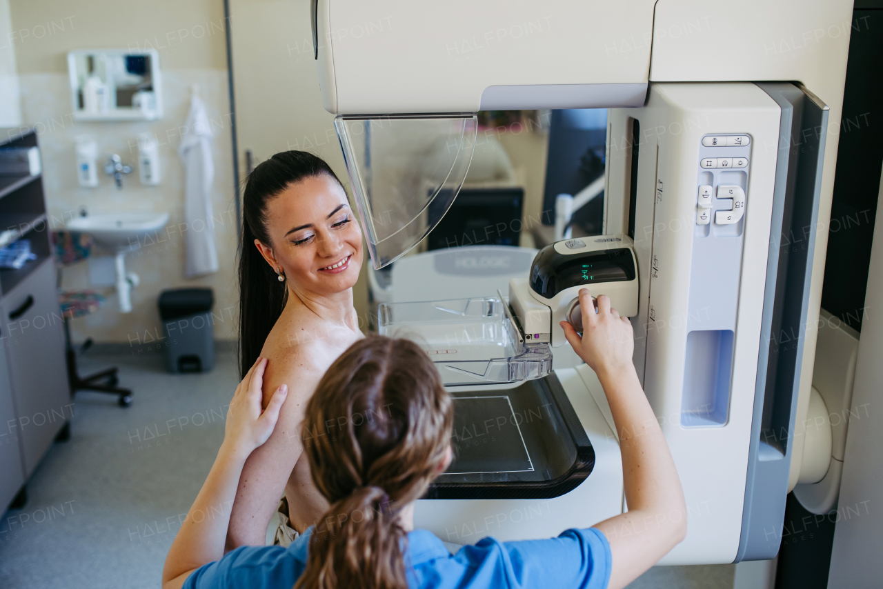 Nurse adjusts the patient for accurate breast imaging. Preventive breast cancer screening.