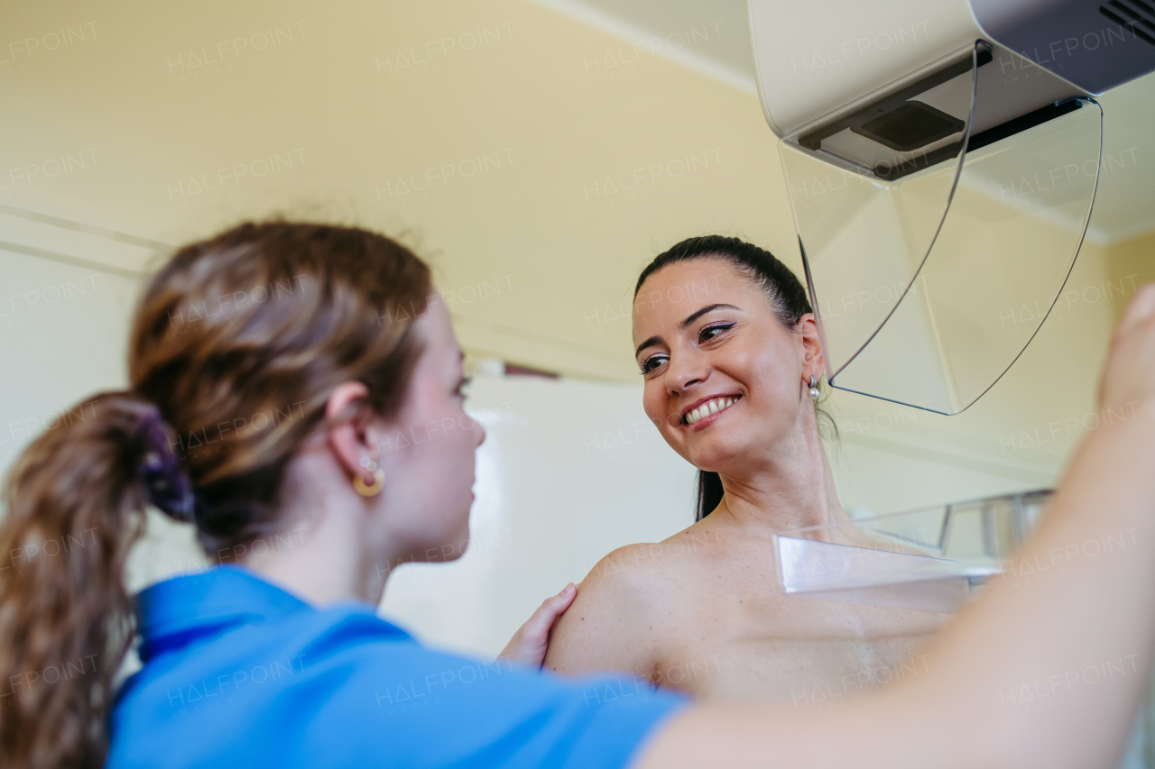 Nurse adjusts the patient for accurate breast imaging. Preventive breast cancer screening.