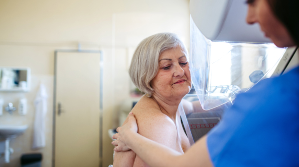 Radiology nurse helping senior woman with mammogram