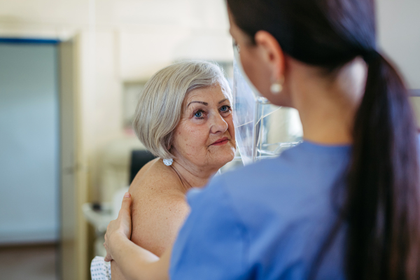 Healthcare worker performing mammography on older woman