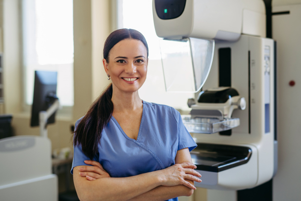 Confident radiology nurse standing by mammography machine