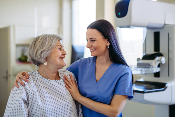 Elderly patient and female nurse looking at each other and smiling. Senior health care.