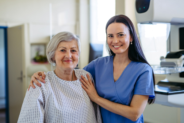 Elderly patient and female nurse looking at camera, smiling. Senior health care.