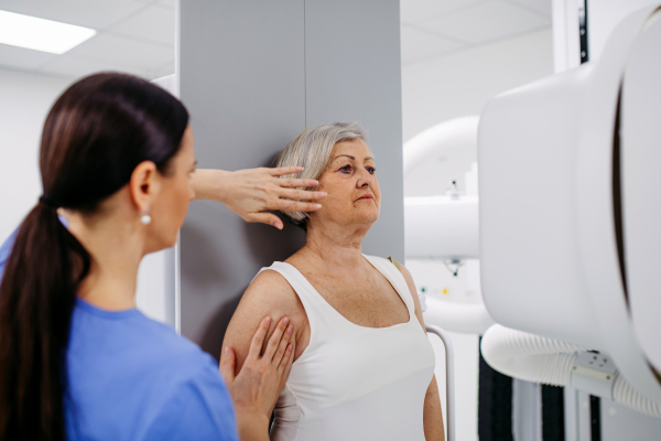 Senior woman positioned on radiographic wall stand for diagnostic imaging