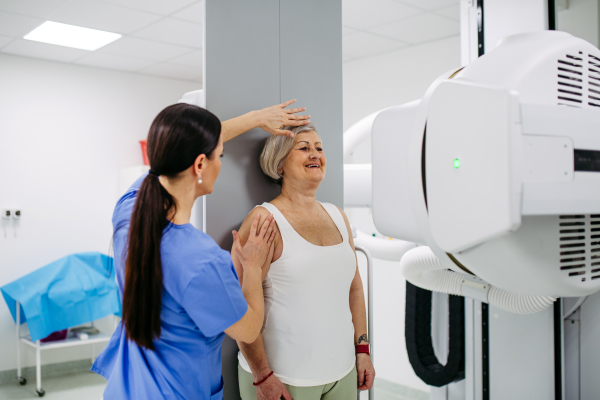 Senior woman positioned on radiographic wall stand for diagnostic imaging