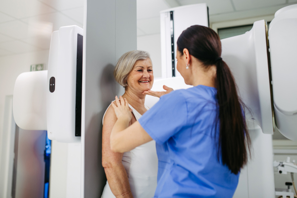 Senior woman positioned on radiographic wall stand for diagnostic imaging