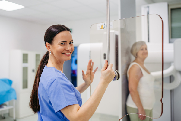 Senior woman positioned on radiographic wall stand for diagnostic imaging