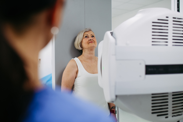 Senior woman positioned on radiographic wall stand for diagnostic imaging