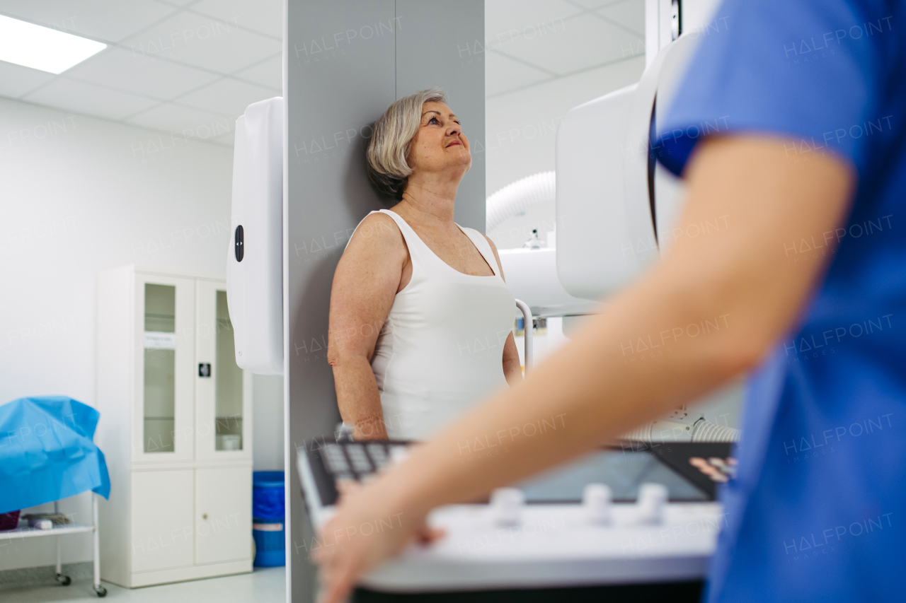 Senior woman positioned on radiographic wall stand for diagnostic imaging