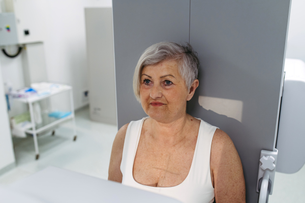 Senior woman positioned on radiographic wall stand for diagnostic imaging