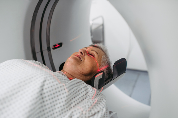 Senior undergoing head scan with laser guidance in CT machine