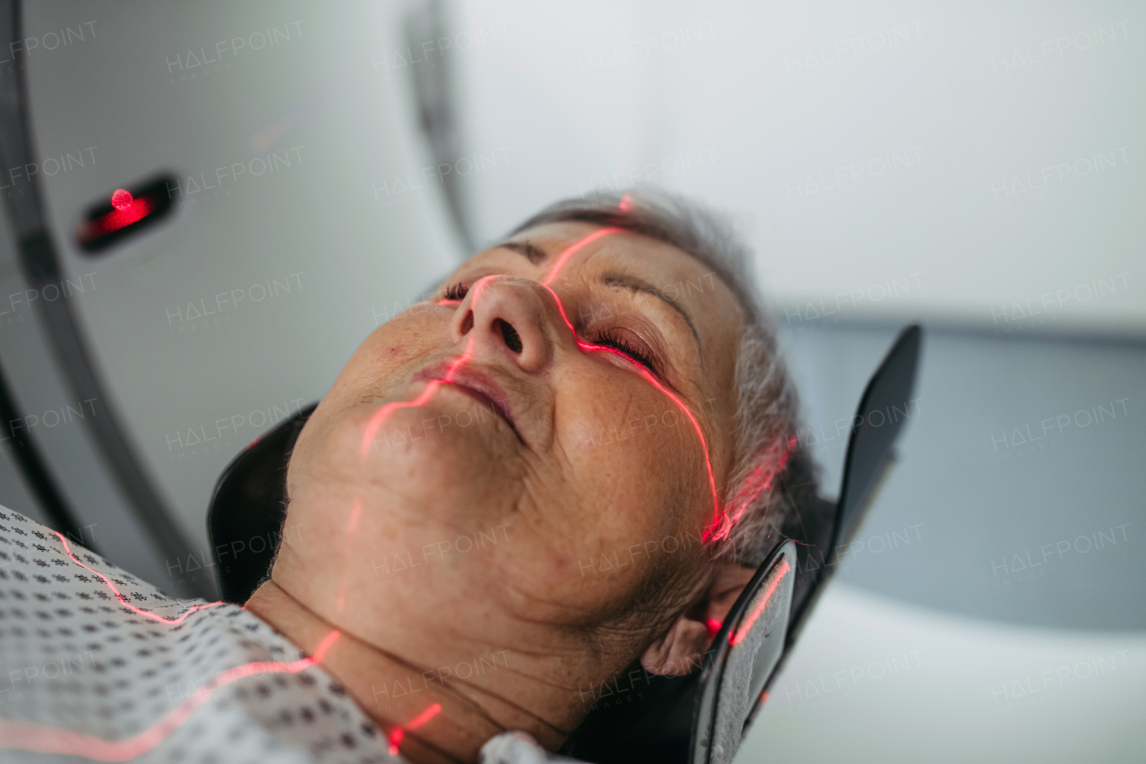 Senior patient positioned for head scan with laser alignment in CT scanner