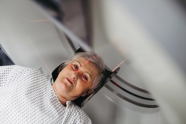 Senior patient positioned for head scan with laser alignment in CT scanner