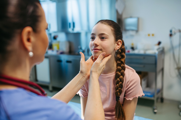 Pediatrician palpating lymph nodes during routine health check.