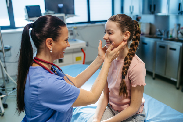 Doctor examining girl's neck for swollen lymph nodes.