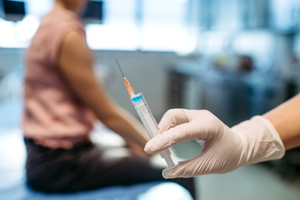 Close-up of vaccine injection in nurse's hand.