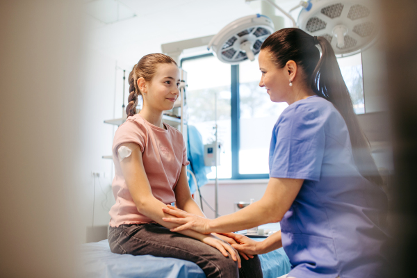Smiling pediatric nurse reassuring child post vaccination.