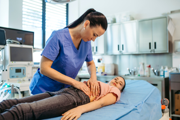 Child lying on exam table during health screening, abdominal palpation