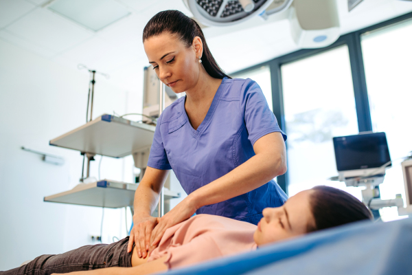 Female doctor palpating girl's abdomen during preventive checkup.