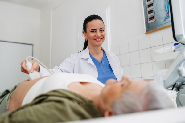 Doctor performing abdominal ultrasound on elderly woman. Preventive care.