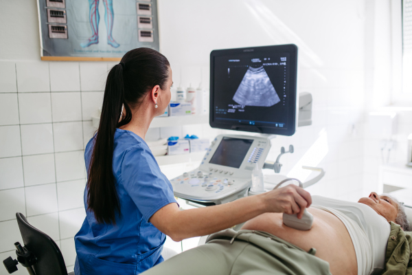 Doctor performing abdominal ultrasound on elderly woman. Preventive care.