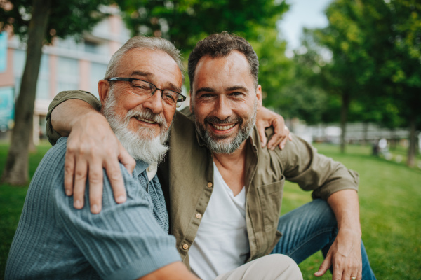 Handsome mature man hugging his older father in park. Fathers day concept.