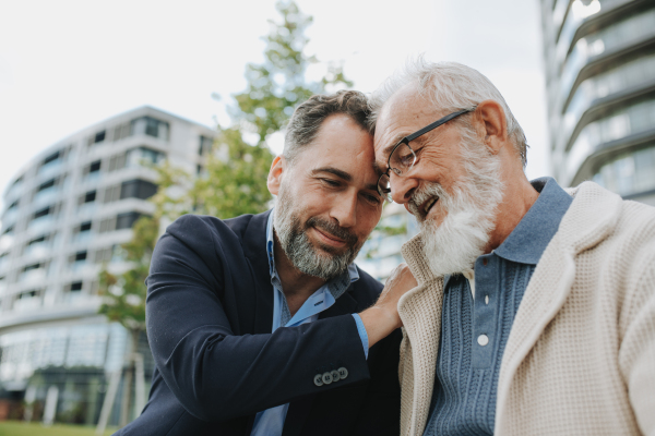 Father and adult son sharing a joyful moment outdoors. Fathers day concept.