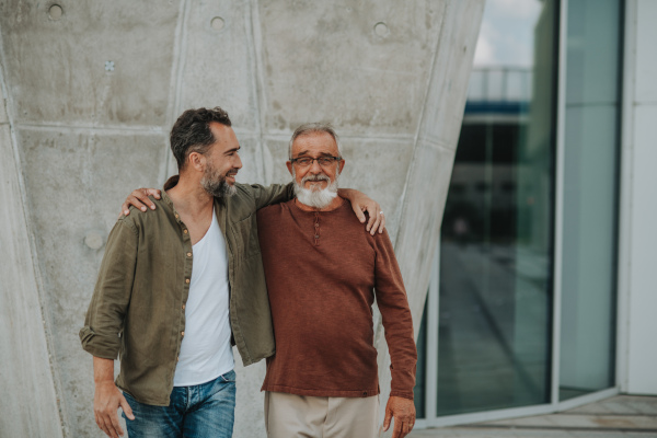 Portrait of handsome mature man and his older father hugging each other. Fathers day concept.