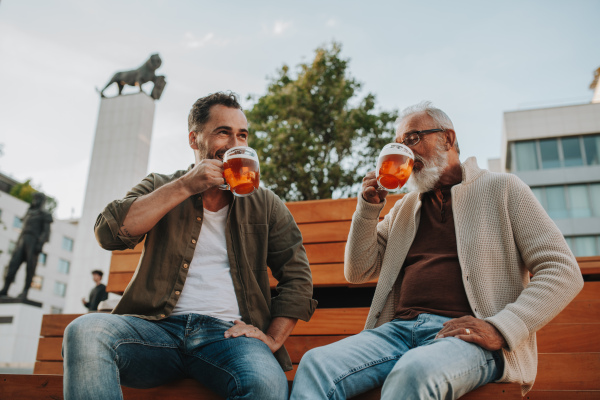 Father and son enjoying beer together outdoors. Fathers day concept.