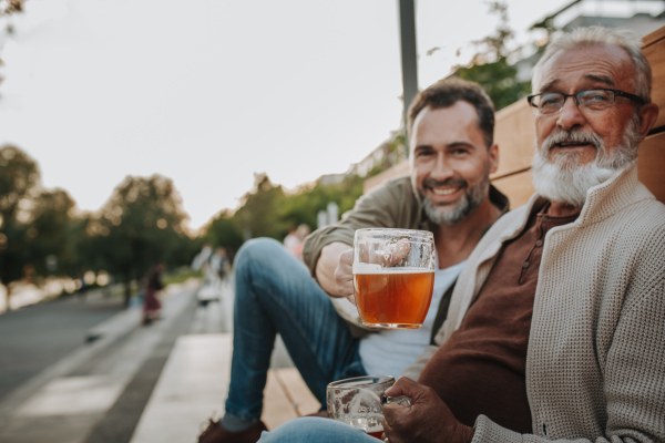 Father and son enjoying beer together outdoors. Fathers day concept.