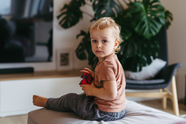 Adorable toddler is playing with a turned-off video game console.