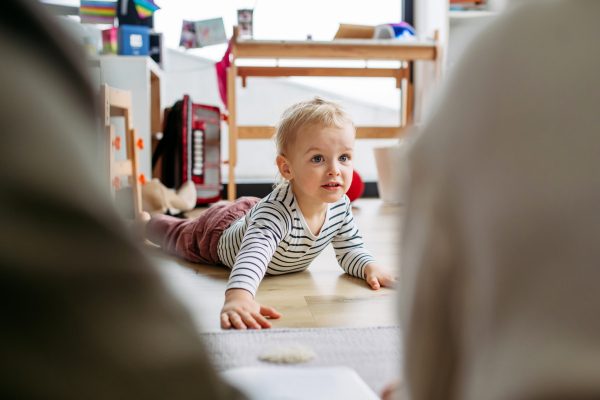 Toddler boy playing on floor in living room, lying on his belly.
