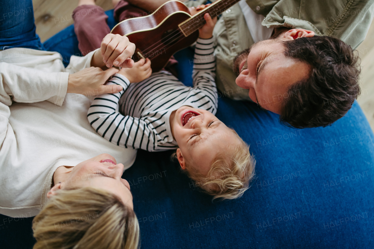 Family bonding moment. Little boy playing on guitar for his family, laughing.