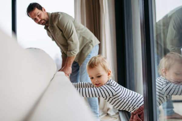 Father and toddler son moving couch together at home