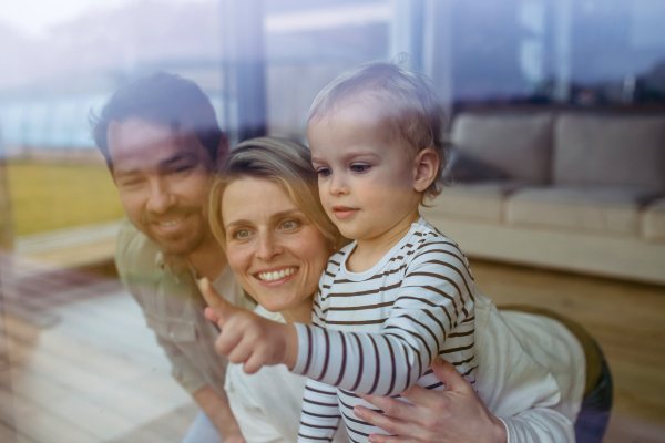 Parents and little boy looking out of window, lying on floor.