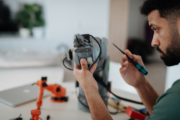 Side view of engineer building and programming a robotic arm at home. Robotics concept.