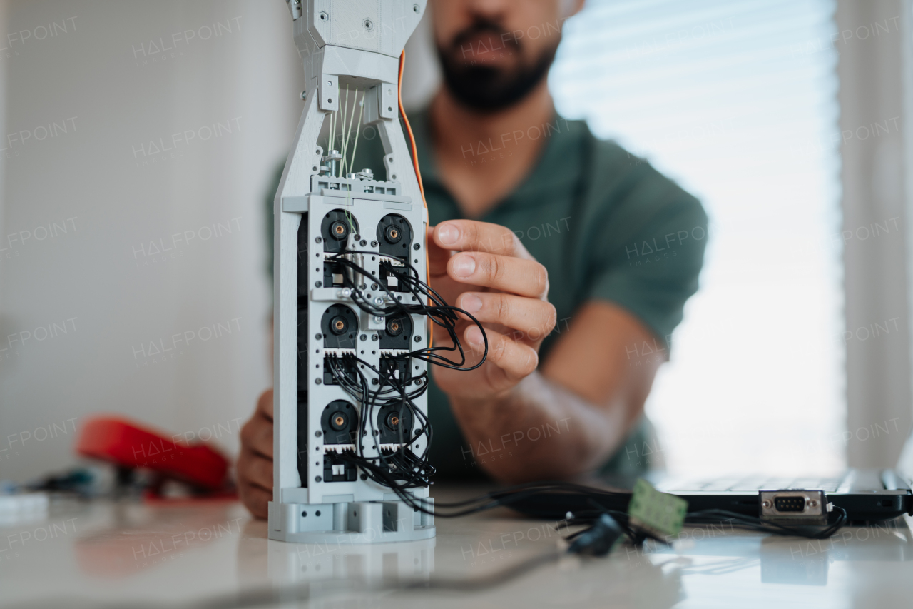 Close up of engineer's hands building and programming a robotic hand at home. Robotics concept.