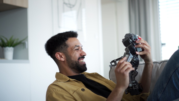Handsome man holding small robot and playing with it, laughing.