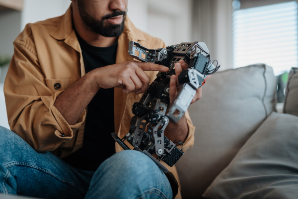 Handsome engineer student working on robot project at home. Robotics concept.