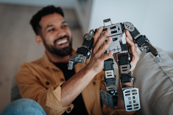 Handsome engineer student working on robot project at home. Robotics concept.