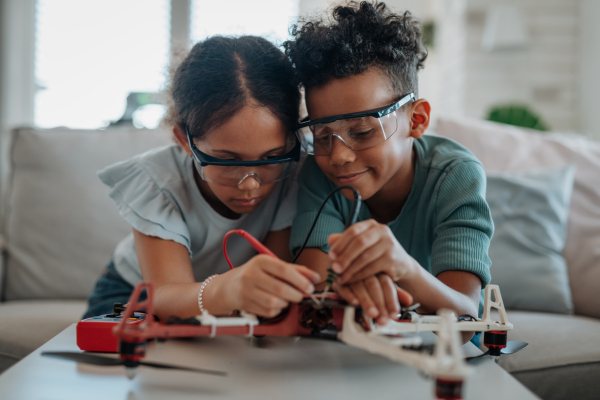 Kids building their first homemade robot at home. Educational robotic kit for children.
